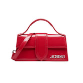 Jacquemus Le Bambino Bag in vibrant red, featuring a sleek, structured design and a top handle. The handbag is made from smooth leather, showcasing minimalist aesthetics and a bold color, perfect for a stylish women's accessory."