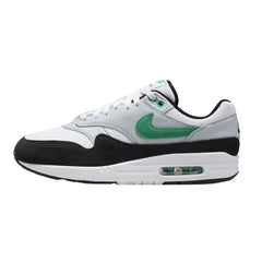 Nike Air Max 1 "Stadium Green" sneakers featuring a combination of white and stadium green suede and mesh materials. The classic silhouette includes black accents on the swoosh and heel, along with a visible Air unit in the midsole, displayed against a neutral background to emphasize the shoe's stylish design.