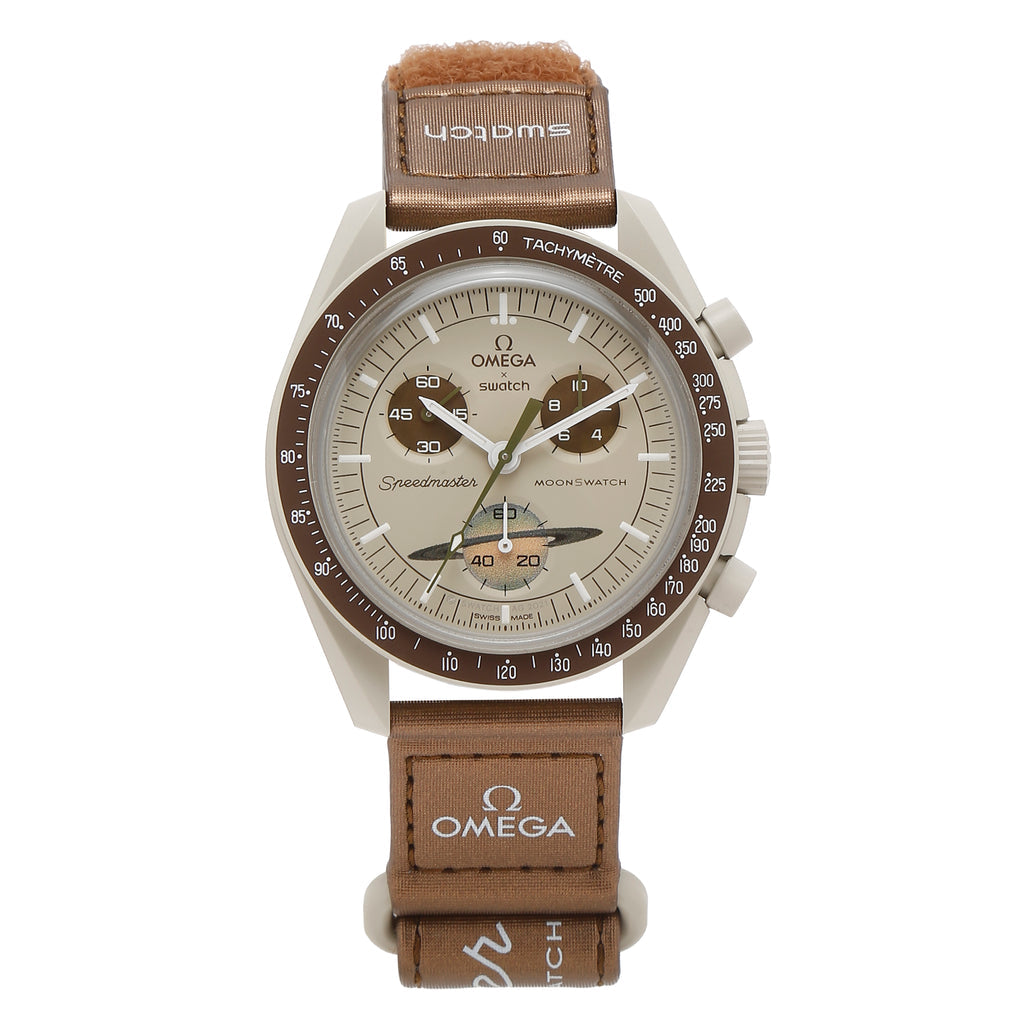 SWATCH X OMEGA BIOCERAMIC MOONSWATCH MISSION TO SATURN the brown dial and VELCRO strap contrast beautifully with the sandy, cold beige tones. The tachymeter scale backdrop, subdial hands, and chronograph seconds hand are all brown as well. Saturn's rings are shown on the seconds subdial.
