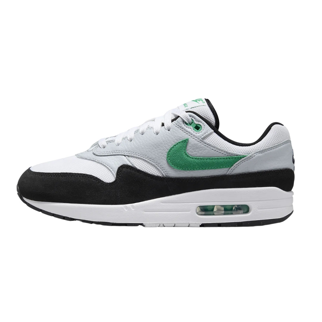 Nike Air Max 1 "Stadium Green" sneakers featuring a combination of white and stadium green suede and mesh materials. The classic silhouette includes black accents on the swoosh and heel, along with a visible Air unit in the midsole, displayed against a neutral background to emphasize the shoe's stylish design.



